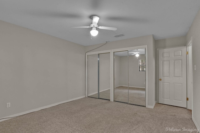 unfurnished bedroom featuring light carpet, two closets, and ceiling fan