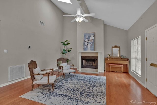 sitting room with a skylight, high vaulted ceiling, ceiling fan, and light wood-type flooring