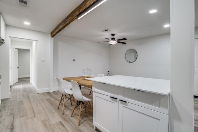 kitchen with beamed ceiling, white cabinetry, ceiling fan, light stone countertops, and light hardwood / wood-style flooring