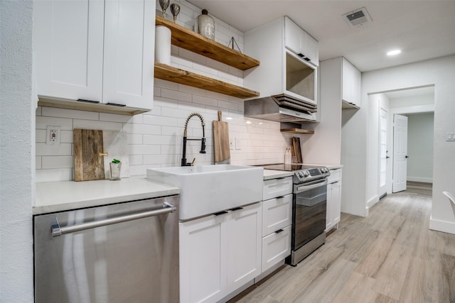 kitchen with sink, light wood-type flooring, white cabinets, and appliances with stainless steel finishes