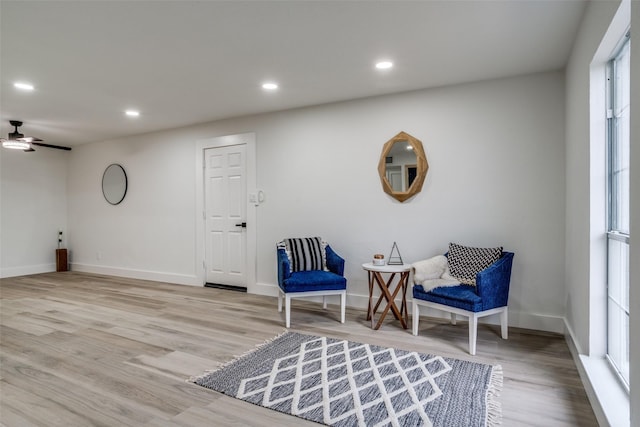 living area with light hardwood / wood-style floors and ceiling fan