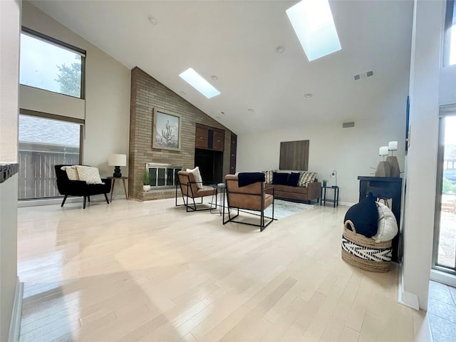 living room with a skylight, visible vents, a fireplace, and light wood-style flooring