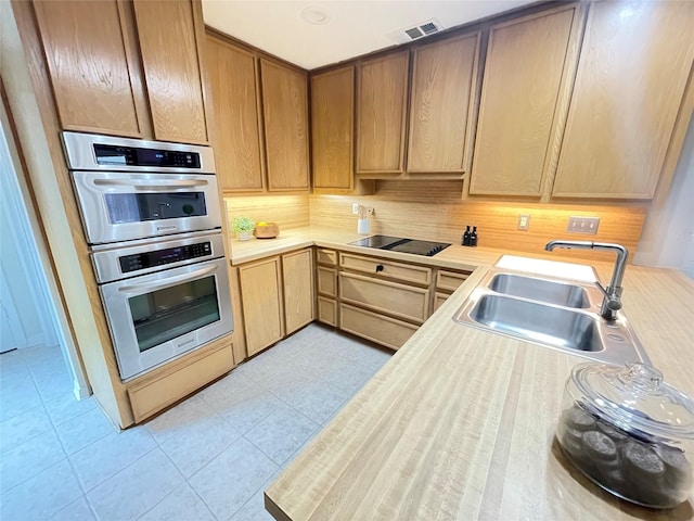 kitchen featuring double oven, black electric stovetop, a sink, visible vents, and light countertops