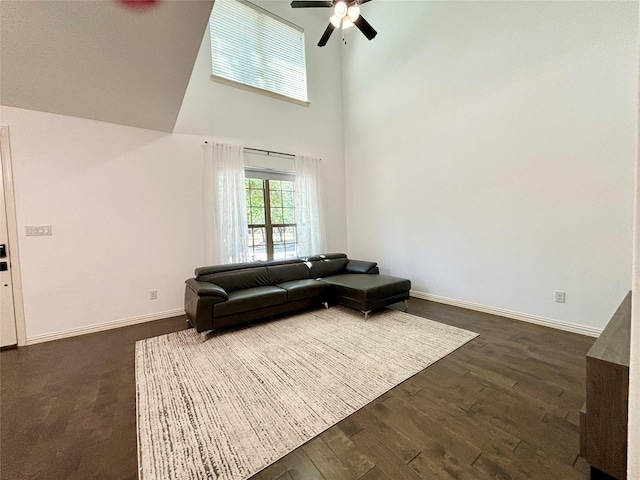 living room featuring dark hardwood / wood-style flooring, ceiling fan, and a high ceiling