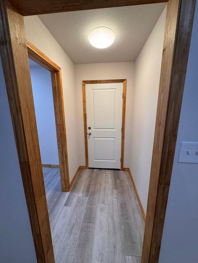 corridor featuring light hardwood / wood-style floors and a textured ceiling