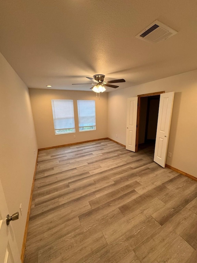 empty room featuring ceiling fan, light hardwood / wood-style flooring, and a textured ceiling