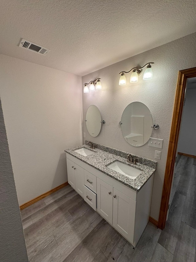 bathroom with hardwood / wood-style flooring, vanity, and a textured ceiling