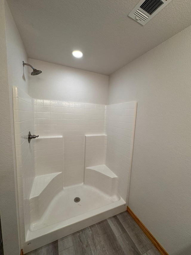 bathroom featuring wood-type flooring, a textured ceiling, and walk in shower