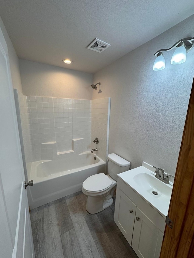 full bathroom featuring toilet, bathing tub / shower combination, a textured ceiling, vanity, and hardwood / wood-style floors