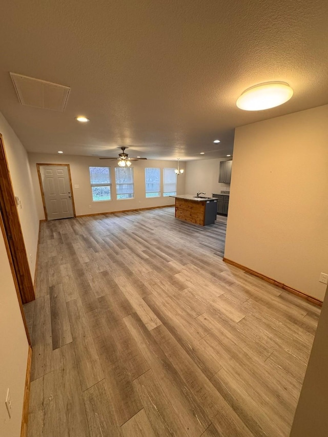 unfurnished living room with ceiling fan, light hardwood / wood-style floors, and a textured ceiling