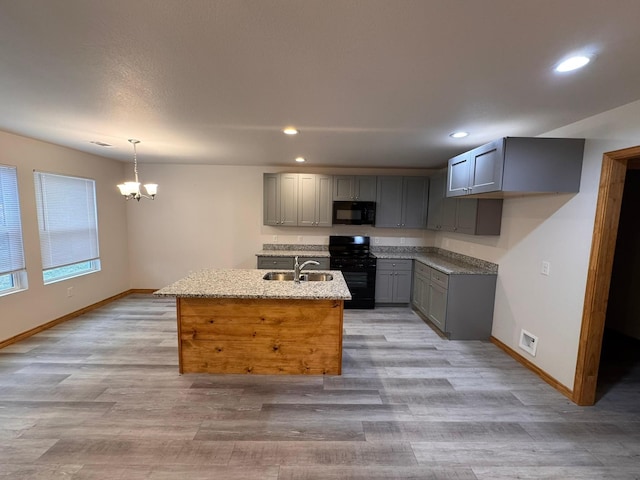 kitchen with sink, light stone counters, decorative light fixtures, gray cabinets, and black appliances