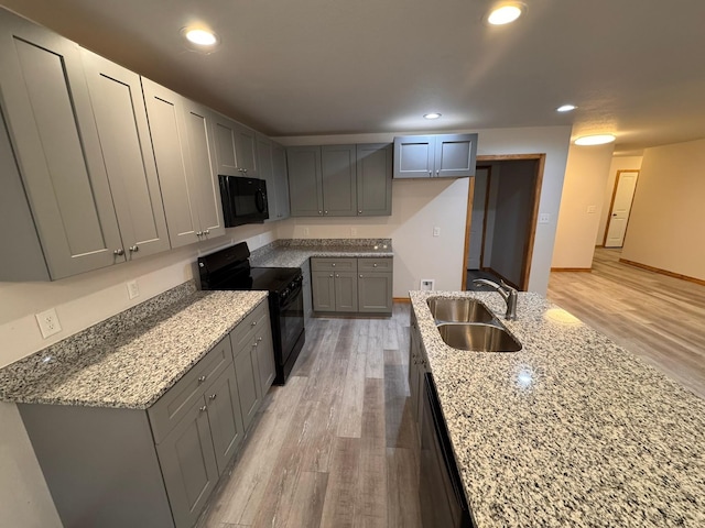 kitchen with gray cabinetry, sink, black appliances, and light stone countertops