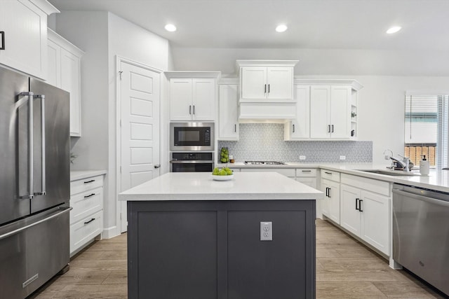 kitchen featuring stainless steel appliances, premium range hood, a sink, and white cabinetry