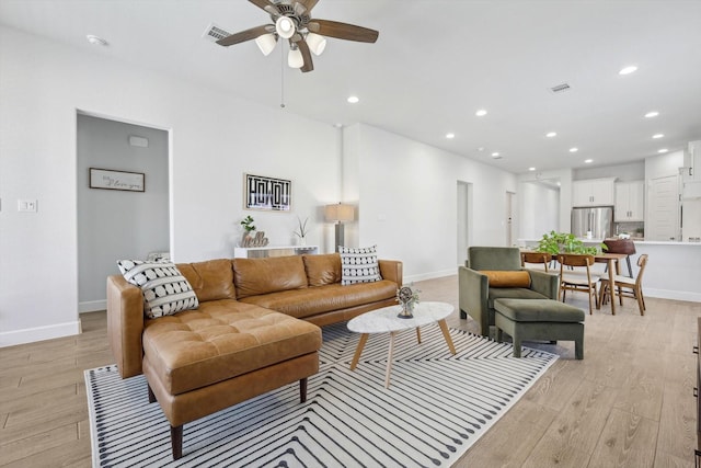 living room featuring light wood-style floors, baseboards, visible vents, and recessed lighting