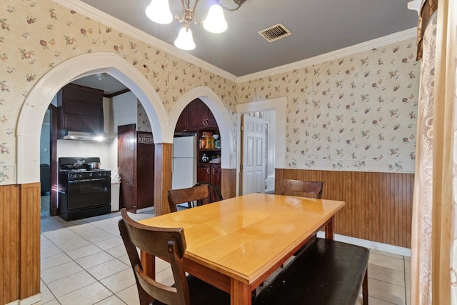 dining room with light tile patterned flooring, ornamental molding, and a notable chandelier