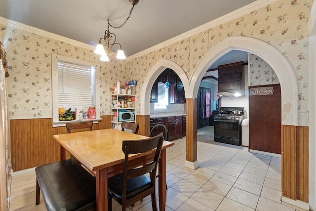 tiled dining room with ornamental molding and an inviting chandelier