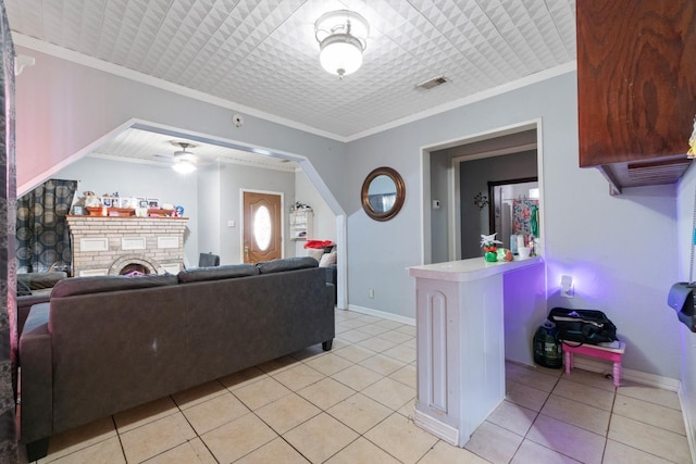 tiled living room featuring crown molding, a fireplace, and ceiling fan