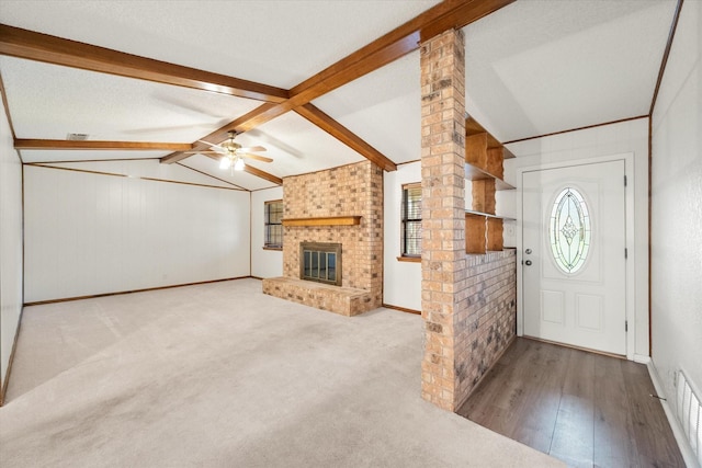 unfurnished living room featuring ornate columns, a fireplace, lofted ceiling with beams, ceiling fan, and a textured ceiling