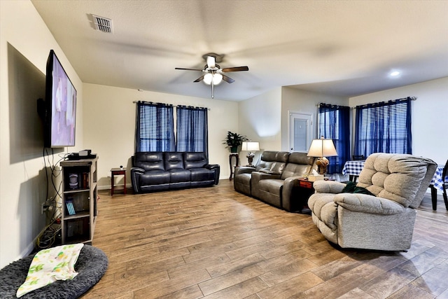 living room with hardwood / wood-style flooring, a textured ceiling, and ceiling fan