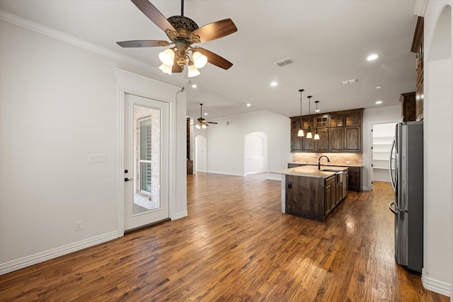 kitchen with stainless steel refrigerator, decorative light fixtures, an island with sink, sink, and dark brown cabinets