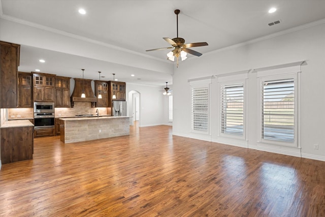 unfurnished living room with sink, crown molding, light hardwood / wood-style flooring, and ceiling fan