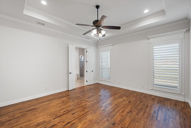 spare room featuring crown molding, dark wood-type flooring, ceiling fan, and a tray ceiling