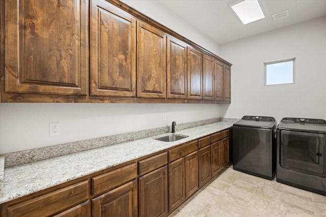 washroom featuring sink, washer and clothes dryer, and cabinets