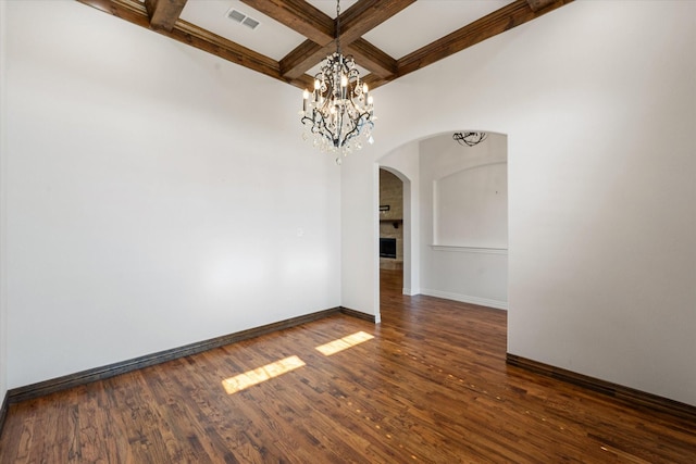 unfurnished room featuring coffered ceiling, dark wood-type flooring, a notable chandelier, and beam ceiling