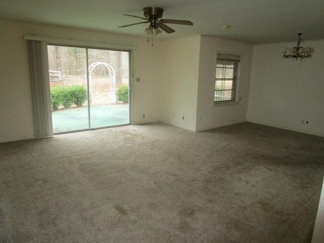 spare room with ceiling fan with notable chandelier and carpet floors