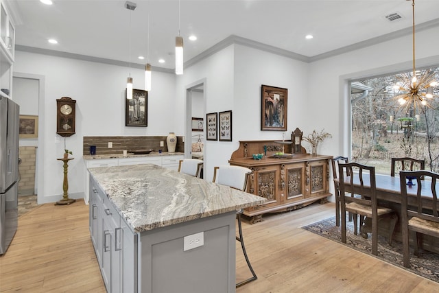 477 Lakepoint Loop, Pottsboro, TX 75076 - kitchen featuring visible vents, a center island, an inviting chandelier, ornamental molding, and light wood-style flooring