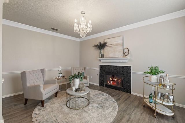 sitting room featuring a textured ceiling, wood finished floors, a chandelier, and a tile fireplace