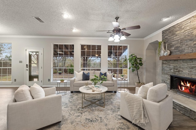 living room with a textured ceiling, ceiling fan, visible vents, and a fireplace