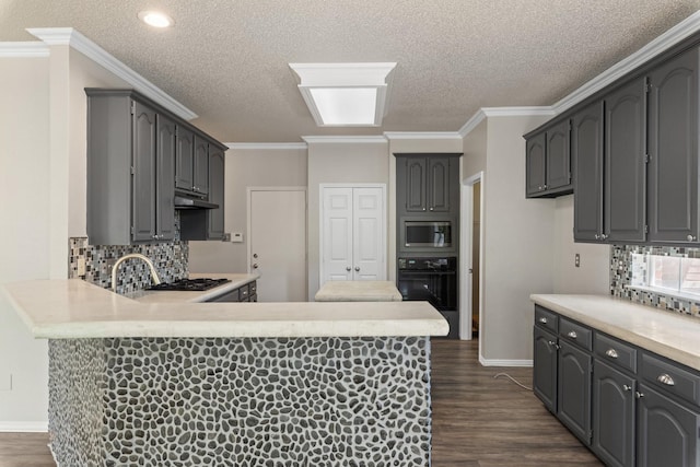 kitchen with a peninsula, black oven, stainless steel microwave, under cabinet range hood, and tasteful backsplash