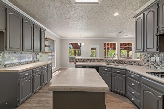 kitchen featuring a center island, a sink, a peninsula, and light countertops