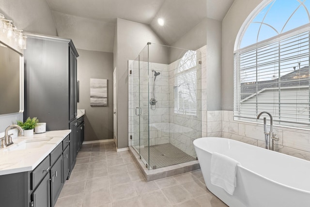 full bathroom with tile patterned flooring, vaulted ceiling, a shower stall, vanity, and a soaking tub