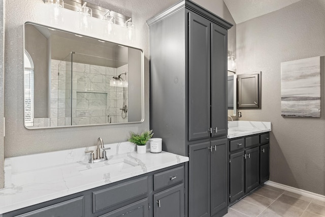 full bathroom with tile patterned flooring, a stall shower, vanity, baseboards, and a textured wall