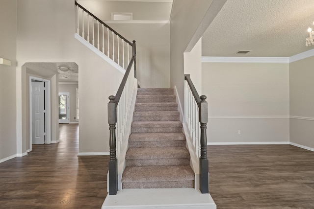 stairway with baseboards, a textured ceiling, visible vents, and wood finished floors