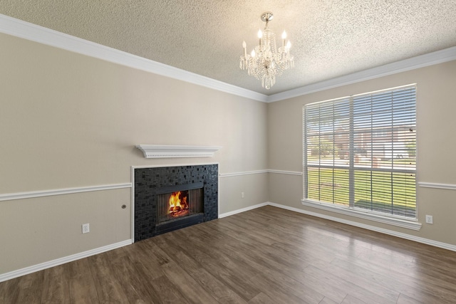 unfurnished living room with a textured ceiling, a notable chandelier, ornamental molding, and wood finished floors