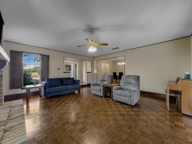 living room featuring dark parquet flooring and ceiling fan with notable chandelier