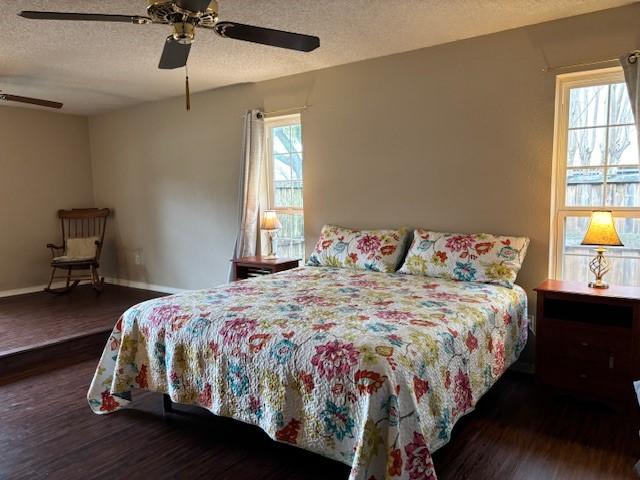 bedroom with ceiling fan, dark wood-type flooring, and a textured ceiling