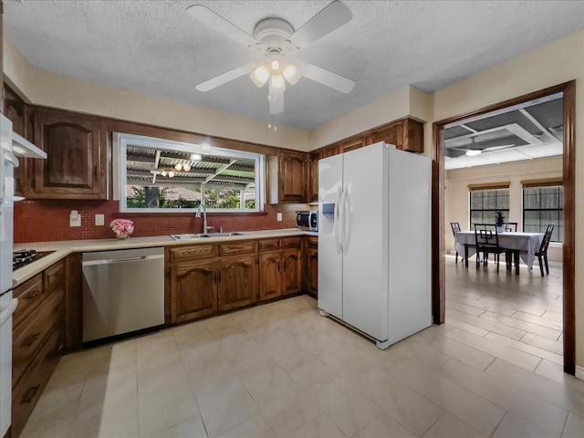 kitchen with appliances with stainless steel finishes, sink, ceiling fan, and decorative backsplash