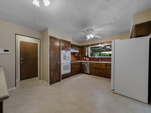 kitchen featuring sink, white appliances, ceiling fan, dark brown cabinets, and a textured ceiling