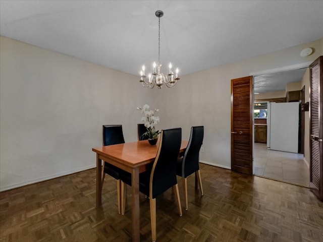 dining space with dark parquet floors and a notable chandelier