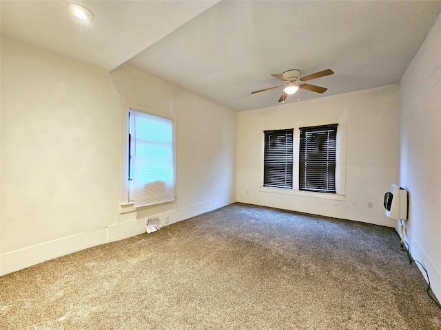 spare room with carpet floors, heating unit, and ceiling fan