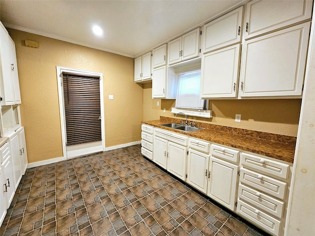 kitchen featuring crown molding, sink, and white cabinets