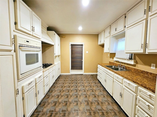 kitchen featuring sink, stainless steel gas stovetop, oven, and white cabinets