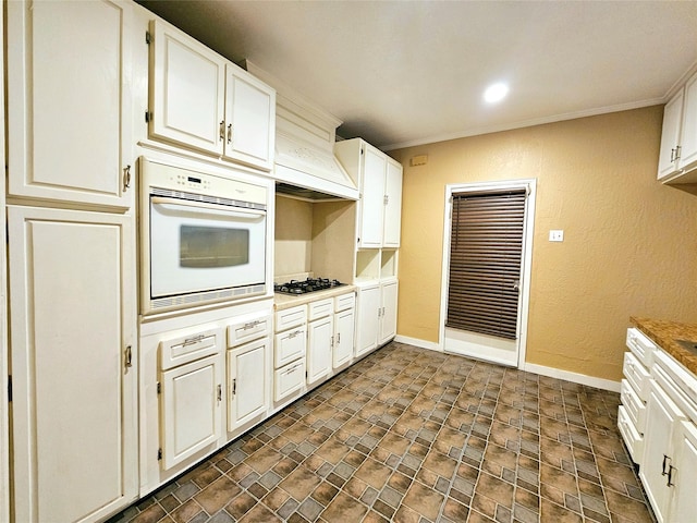 kitchen featuring ornamental molding, stainless steel gas stovetop, white oven, and white cabinets