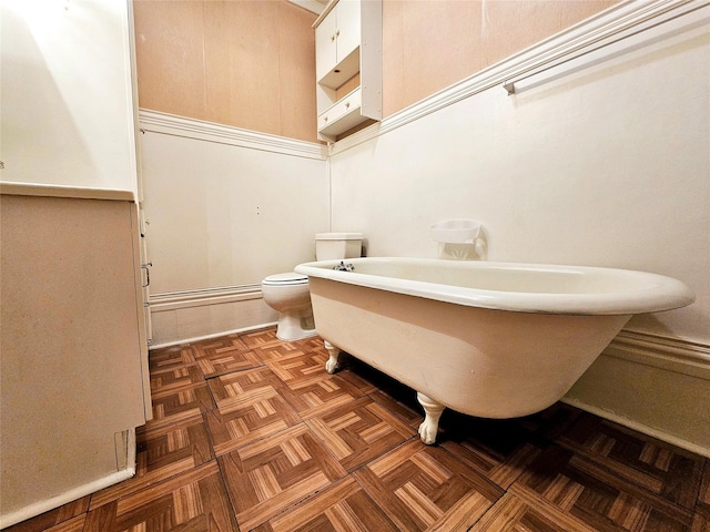 bathroom featuring toilet, parquet floors, and a tub to relax in