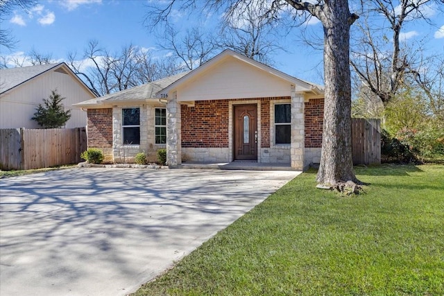 view of front facade with driveway, brick siding, a front yard, and fence