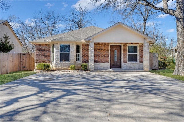 view of front of home with a shingled roof, fence, concrete driveway, and brick siding